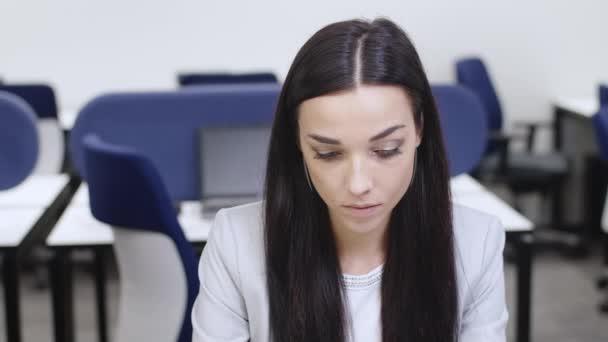 Portrait of busy young beautiful woman sitting in office in the evening as familiar man making a pass to subordinate employee. Gorgeous Caucasian slim lady looking at camera. Confusion concept. — Stock Video