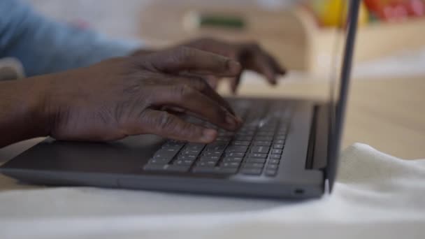 Primer plano de manos afroamericanas masculinas escribiendo en el teclado del ordenador portátil. Hombre confiado ocupado irreconocible que trabaja en línea en la oficina central en el bloqueo pandémico de Covid-19. Nueva normalidad. — Vídeos de Stock