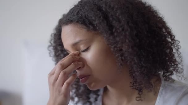 Nahaufnahme einer müden schönen Afroamerikanerin, die sich die Augen reibt, wenn sie zu Hause im Büro arbeitet. Kopfschuss-Porträt eines erschöpften, überlasteten Freiberuflers mit Migräne. — Stockvideo