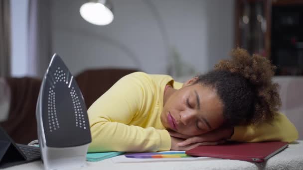 Exhausted young African American woman sleeping on laptop on ironing board in home office. Tired overworked beautiful manager falling asleep on remote working. Overwhelmed employee indoors. — 비디오