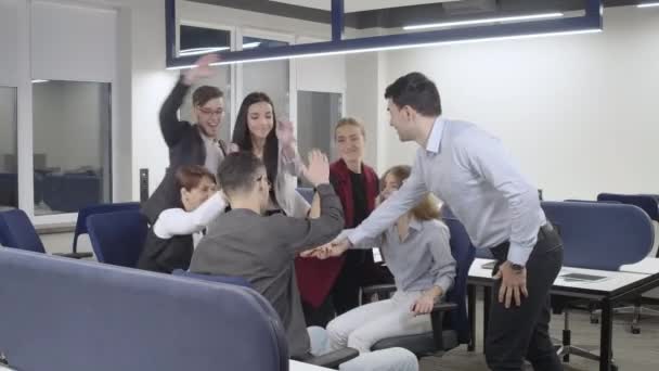 Brede shot van vrolijke mannen en vrouwen stapelen handen verheugen zich zakelijk succes in het kantoor binnen. Positief succesvolle blanke collega 's glimlachend. Organisatie en teamwerk. — Stockvideo