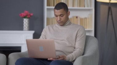 Başarılı genç Afro-Amerikan adam bilgisayarını kapatıp ofisten ayrılıyor. Kendine güvenen zengin bir yöneticinin portresi. E-ticaret ve uzaktan çalışma kavramı.