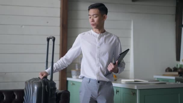 Tankeväckande ung asiatisk man lämnar i slow motion med resväska och tablett. Porträtt av ledsen desperat kinesisk chef förlorade jobbet på coronavirus pandemisk kris gå bort från hemmakontoret. — Stockvideo