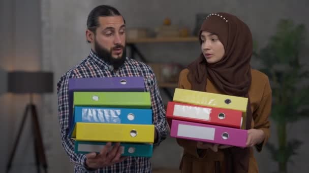 Trött Mellanöstern par står i hemmakontoret innehav dokument mappar suckande. Porträtt av överväldigad man och kvinna överbelastad med multitasking fjärrarbete poserar i vardagsrummet. — Stockvideo