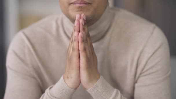 Jeune homme afro-américain méconnaissable tenant la main en priant. Sérieux religieux concentré demandant de l'aide à Dieu. Concept d'espoir et de croyance. — Video