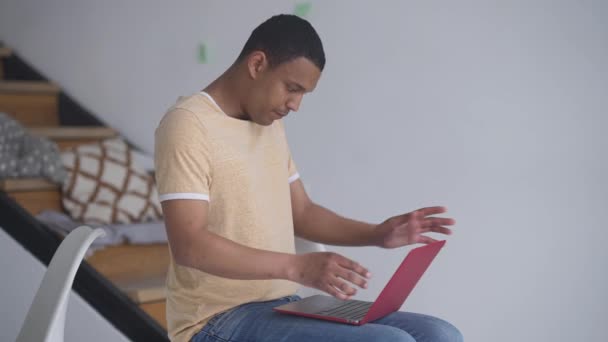 Widok z boku Afroamerykanina na laptopie, stojącego i biegającego na górze w biurze. Pomyślny pozytywny młody menedżer pracujący online w pomieszczeniach. — Wideo stockowe