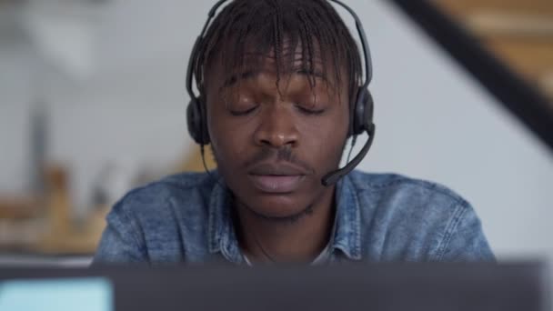 Gros plan du visage d'un jeune homme épuisé frottant les yeux au ralenti assis à table avec un ordinateur portable au bureau à la maison. Surmenage fatigué Afro-Américain surchargé de travail à distance. — Video