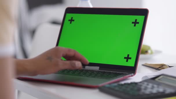 Großaufnahme-Laptop mit grünem Bildschirm und männlicher afroamerikanischer Tätowierung auf der Tastatur. Unbekannter surft im Home Office im Internet-Messaging. Chromakey-Gerät. — Stockvideo