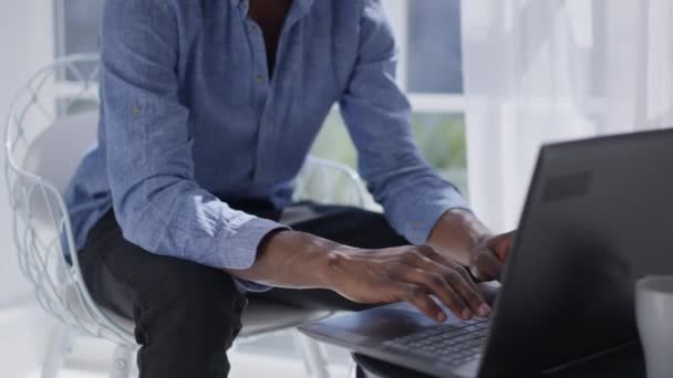 Homem afro-americano irreconhecível digitando no teclado do laptop pela manhã no home office. Analista profissional de negócios gerente de mensagens on-line verificando e-mail dentro de casa no trabalho remoto. — Vídeo de Stock