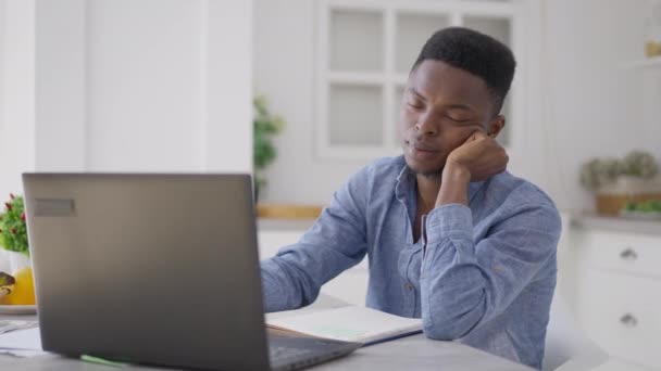 Tired exhausted young man falling asleep sitting at kitchen table in home office. Portrait of overworking overburdened African American manager suffering insomnia on remote working. — Vídeo de stock