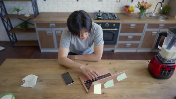 亚洲年轻人在笔记本电脑键盘上打字、上网发短信的头像。自信集中的在线分析师坐在厨房台面的办公室里工作. — 图库视频影像