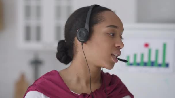 Fejkép unatkozó, elégedetlen fiatal hölgyről, aki fejhallgatóban sóhajtozik, miközben a kamerába néz. Virtuális konferencia POV bosszús irritált afro-amerikai munkavállalói konferenciák online otthoni irodából. — Stock videók