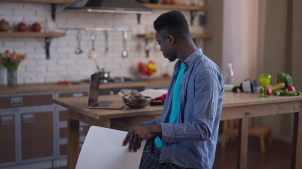 Afro-amerikan bir gencin kahvaltısını mutfakta yerken kağıt işlerini analiz etmesi. Sabahleyin merkez büroda akıllı bir iş adamı planlama stratejisi uygulanıyor.. — Stok video