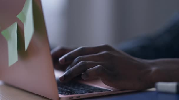 Egy közeli afroamerikai férfi gépel a laptop billentyűzetén lassított felvételen. Felismerhetetlen fiatalember üzeneteket küld az interneten szörfözve az otthoni irodában. Üzleti koncepció. — Stock videók