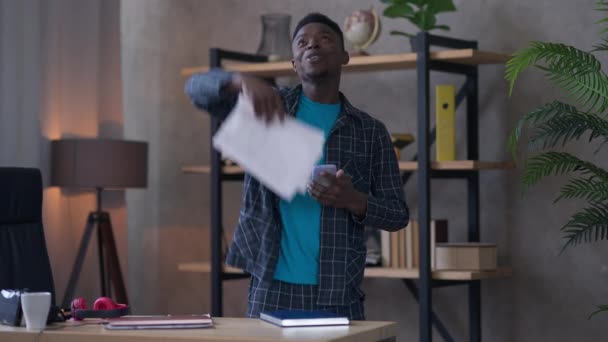 Emocionado hombre afroamericano feliz dispersando documentos comprobando el correo electrónico en el teléfono inteligente. Retrato de alegre joven startuper positivo regocijando el éxito del negocio de pie en el Ministerio del Interior. Logro. — Vídeo de stock