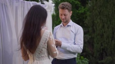 Canlı kamera, mutlu gülümseyen beyaz bir adamın Orta Doğulu bir kadının elini öperken parmağına yüzük takmasına odaklan. Sevecen, mutlu damat bahçede gelinle evleniyor..