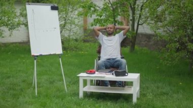 Tekerlekli sandalyede oturup bahar bahçesinde düşünen düşünceli bir erkek serbest yazar. Engelli Afro-Amerikan bir adamın açık havada bir şeyler planlama portresi. İlham ve iyimserlik.