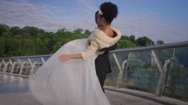 Mutlu Afrikalı Amerikalı zarif damat, yaz köprüsünde elleri üzerinde dönen gelini tutuyor. Romantik heyecanlı bir çift yeni evli çift açık havada evliliğin tadını çıkarıyor. Yakınlaşma ve romantizm. Yavaş çekim.