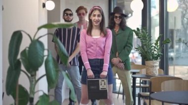 Kahve barında bir grup arkadaşıyla dans eden çekici, zayıf retro kadın. 1980 'lerin mutlu beyaz kadın portresi. Kalçalarını oynatıyor. Elinde antika bir teyp var. 1990 'ların eğlence ve yaşam tarzı.