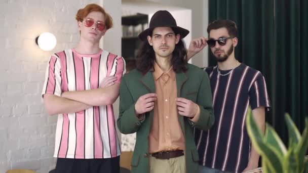 Retrato de tres hombres retro con estilo de pie en el interior mirando a la cámara con expresión facial segura. Foto mediana de joven guapo dandy caucásico posando en 1980. Concepto de confianza. — Vídeo de stock