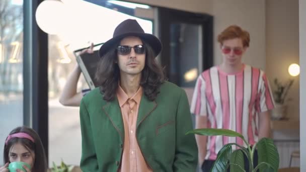 Three confident retro dandy men with vintage tape recorder on shoulder leaving vintage coffee shop. Young friends walking away with serious facial expression. 1980s lifestyle and friendship. — Stock Video