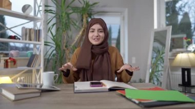 İnternette konuşan ve gülümseyen neşeli Orta Doğulu kadın blogcu görüntüsü var. Güzel, pozitif bir genç kadın evde blog yazıyor. Modern yaşam tarzı ve uzak çalışma.