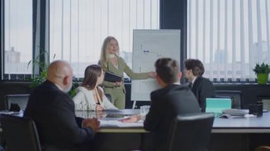 Bir grup meslektaşın konferans masasında el çırparken beyaz tahtada duran muhteşem, kendine güvenen beyaz iş kadını iş fikrini sunuyor. İş takım çalışması konsepti.