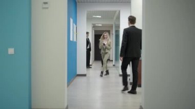 Ofis koridorunda yürümekle meşgul iş adamları. Koridordan geçen kendine güvenen erkek ve kadınlar. İş yerinde rutin ve istihdam kavramı.