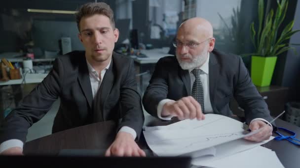Young and middle aged men analyzing business project as woman passing with documents consulting managers. Medium shot of confident professional people working in office indoors. — Stock video