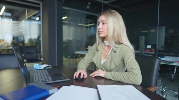 Portret van een geconcentreerde blanke vrouw die aan tafel zit met laptop en documenten. Prachtige blonde dame die de boekhouding binnen analyseert. Lifestyle en vertrouwen. — Stockvideo