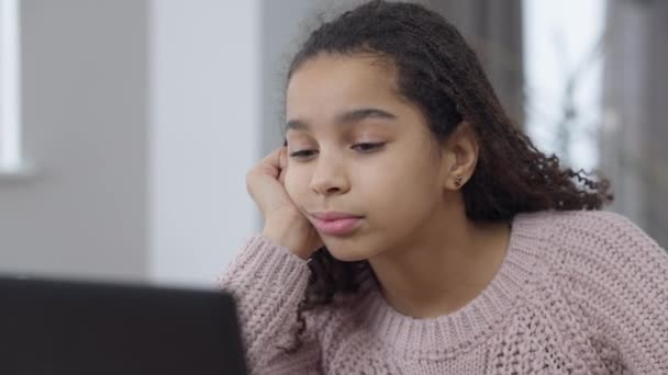 Gros plan portrait de s'ennuyer fatigué afro-américaine jolie fille s'endormir devant un ordinateur portable regarder leçon en ligne. Adolescent épuisé apprenant de la maison sur le confinement pandémique de coronavirus. — Video