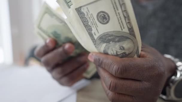 近くの男性アフリカ系アメリカ人の手はお金を数える。認識できない若い男が家の中で現金ドルを計算。財政と豊かさの概念. — ストック動画