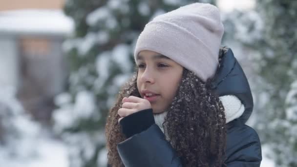 Tosse afro-americano adolescente menina pulverizando spray de garganta em pé ao ar livre no dia frio de inverno. Retrato de adolescente doente no quintal. Conceito de cuidados de saúde e tempo. — Vídeo de Stock