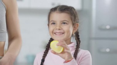 Neşeli tatlı Orta Doğulu kız blender 'a limon koyuyor ve annesinin sağlıklı meyve suyu hazırlamasına yardım ediyor. Evde ailesiyle yemek pişiren güzel bir kızın portresi..