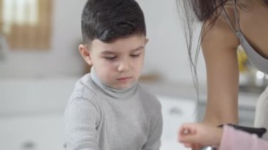 Orta Doğulu sevimli bir çocuğun portresi. Annesinin mutfakta smoothie pişirmesine yardım ediyor. Mutlu yakışıklı oğul, annesiyle evde sağlıklı bir kokteyl hazırlıyor. Yaşam tarzı ve aile kavramı.