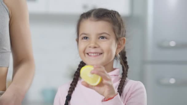 Menina alegre bonito Oriente Médio colocando limão no liquidificador ajudando a mãe a preparar smoothie saudável. Retrato de encantadora filha bonita cozinhar com os pais em casa dentro de casa. — Vídeo de Stock