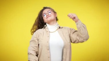 Aşırı kilolu neşeli bir kadın sarı arka plana saçlarını savuruyor ve gülümsüyor. Kameraya bakan uzun kıvırcık saçlı neşeli genç Kafkas çağının portresi..