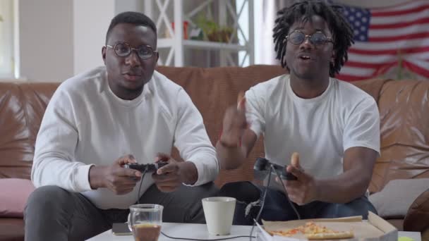 Milenyum Afro-Amerikan erkekleri çok oyunculu video oyununda coşkulu bir zafer kazandılar. Mutlu gülen yakışıklı arkadaşlar hafta sonu kapalı alanda dinleniyor.. — Stok video