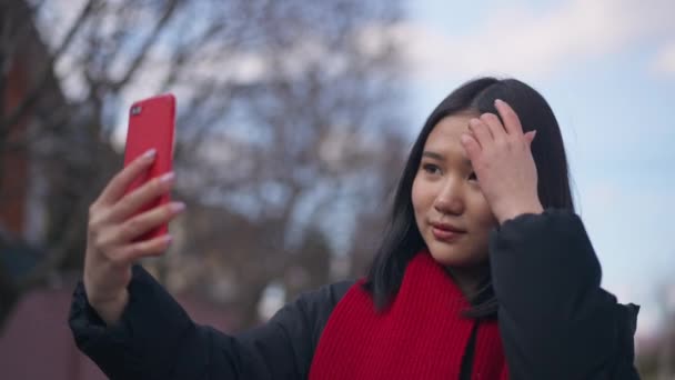 Mujer joven asiática tomando selfie en el teléfono inteligente de pie al aire libre. Retrato de feliz despreocupado millennial viajando tomando fotos en el teléfono. Estilo de vida moderno y concepto de redes sociales. — Vídeos de Stock