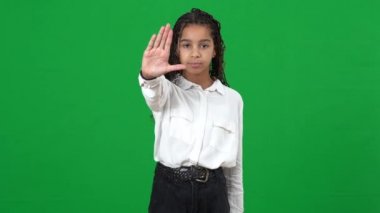 Kendine güveni tam, Afro-Amerikalı genç kız kameraya el ele esniyor. Yeşil ekranda başını sallama hareketi yapma. Kromakey arka planında poz veren gençlerin portresi reddedilmeyi tasvip etmiyor.