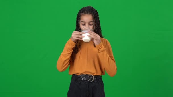 Tonåring afroamerikansk flicka dricker mjölk visar tummen upp tittar på kameran leende. Porträtt av glada nöjda tonåring dricker hälsosam vitamin mejeri på grön skärm kromakey. — Stockvideo