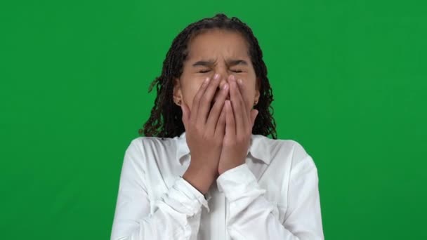 Retrato de cerca de la adolescente aburrida afroamericana bostezando en la pantalla verde. Hermosa adolescente mirando la cámara en el fondo cromakey. Concepto de aburrimiento y cansancio. — Vídeo de stock