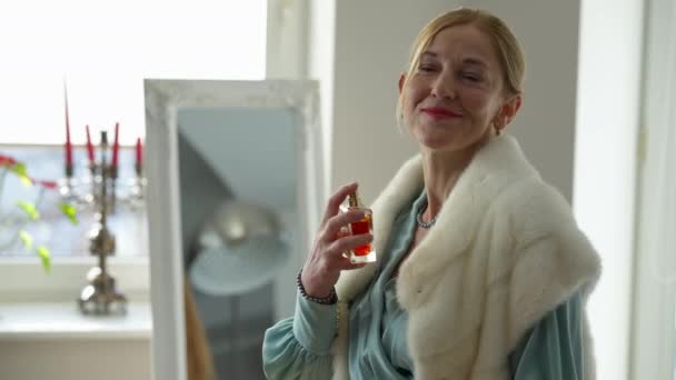 Narcissique confiant femme riche d'âge moyen pulvérisation parfum souriant. Portrait de femme riche Caucasienne réussie se préparer à la maison à l'intérieur. Haute société et concept de luxe. — Video