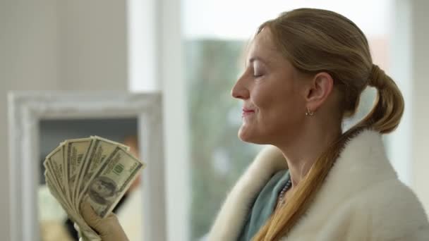 Elégedett gazdag középkorú nő használja készpénz, mint a rajongó mosolyog otthon. Portré magabiztos gazdag kaukázusi hölgy elegáns kesztyű és ruha élvezi luxus otthon. — Stock videók