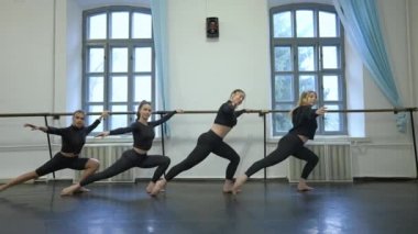 Stüdyodaki dans barlarında dört muhteşem, kendine güvenen genç beyaz dansçının geniş açılı çekimi. Bir grup profesyonel sanatçı yavaş çekimde içeride prova yapıyor. Koreografi kavramı.