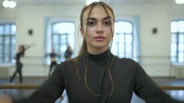 Kendine güvenen esmer kadın stüdyoda dans provası yapıyor arka planda bulanık insanlar var. İnce, çekici Kafkas milenyum eğitim performansı.