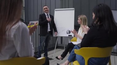 Satisfied successful Caucasian man smiling as colleagues clapping approving strategy idea. Portrait of happy handsome manager presenting startup outdoors for coworkers. Big business.