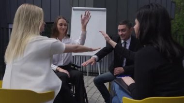 Cheerful business people giving high-five clapping in slow motion smiling. Positive confident Caucasian men and women planning startup strategy on meeting outdoors. Success and lifestyle.