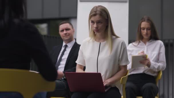 Segretario concentrato digitando sulla tastiera del computer portatile seduto con i colleghi come portavoce parlando. Focalizzato bella bionda donna caucasica registrazione incontro al rallentatore. Concetto stile business. — Video Stock