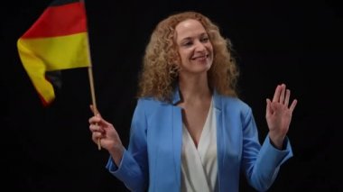 Çekici, kendine güvenen politikacının portresi elinde Alman bayrağı sallayarak etrafa bakıyor. Siyah arka planda basın ve paparazzilere poz veren güzel kadın gülümsüyor..